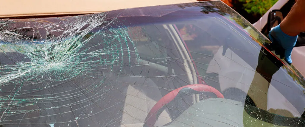 A car with a shattered windshield, posing a safety hazard and requiring immediate repair.